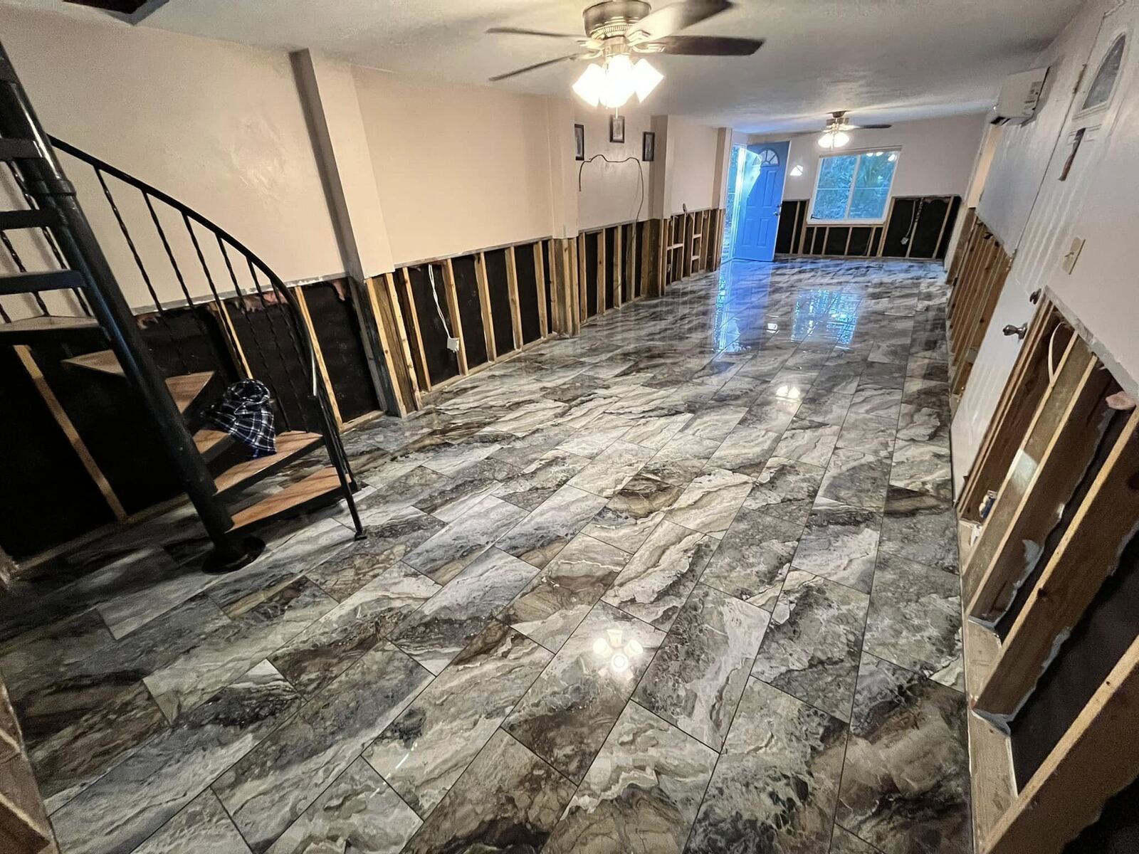 Water damage restoration with new marble-look tile flooring and open wall studs