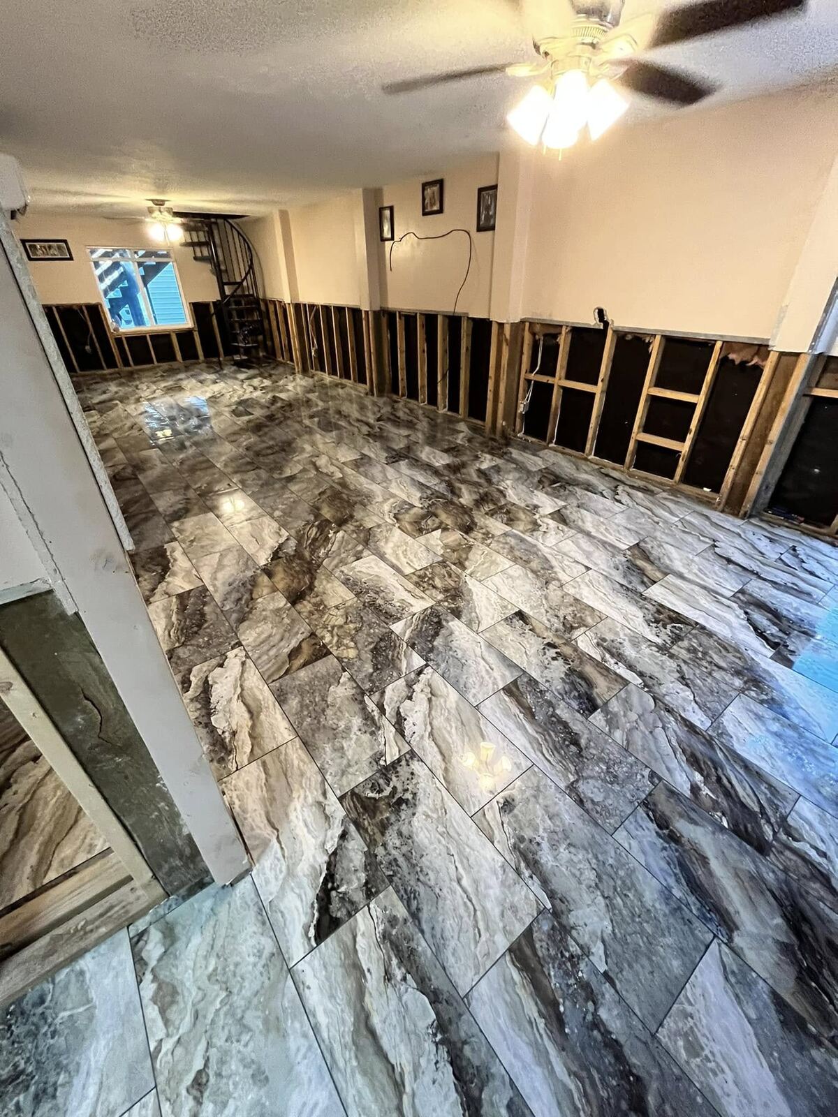 Marble-look tile flooring installation near spiral staircase